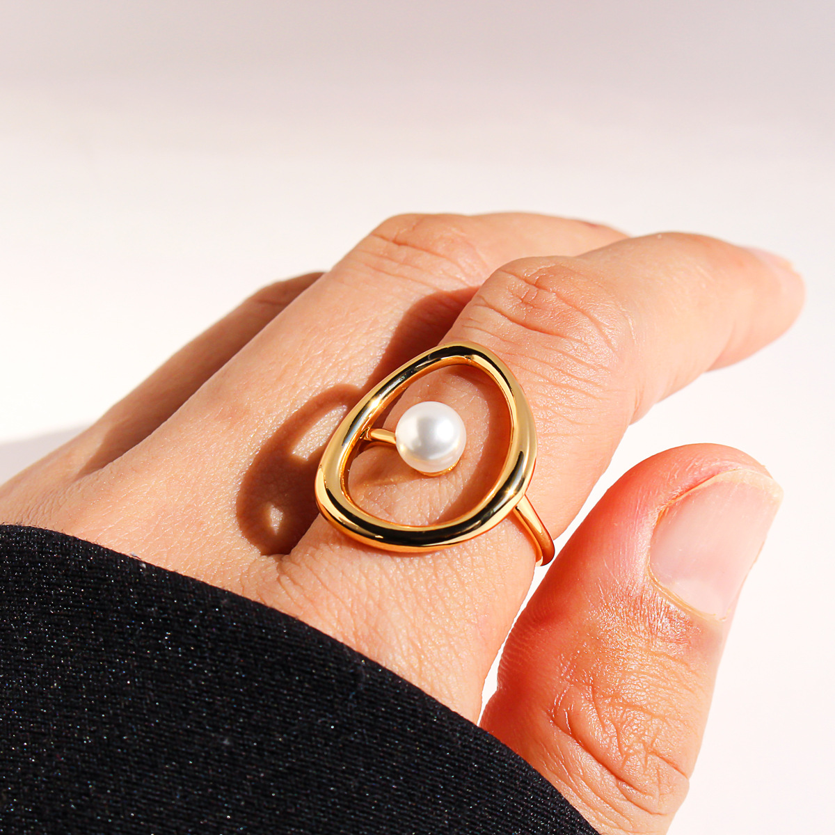 A stylish, abstract pearl ring with a copper-plated, genuine-gold finish and a unique, hollowed-out curved design.