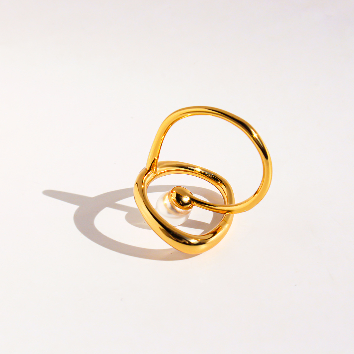 A stylish, abstract pearl ring with a copper-plated, genuine-gold finish and a unique, hollowed-out curved design.