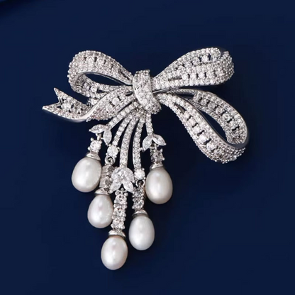 A delicate and luxurious brooch with bow-shaped tassels and a slightly set zirconia embellishment, along with freshwater pearl pins as accessories.