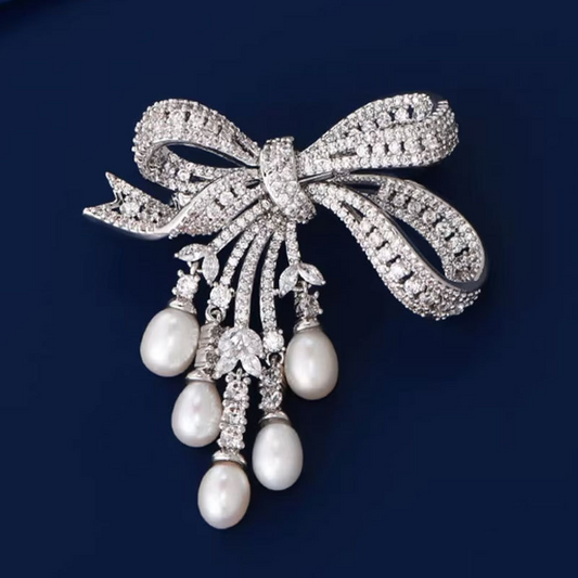 A delicate and luxurious brooch with bow-shaped tassels and a slightly set zirconia embellishment, along with freshwater pearl pins as accessories.