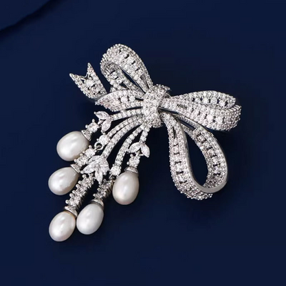 A delicate and luxurious brooch with bow-shaped tassels and a slightly set zirconia embellishment, along with freshwater pearl pins as accessories.