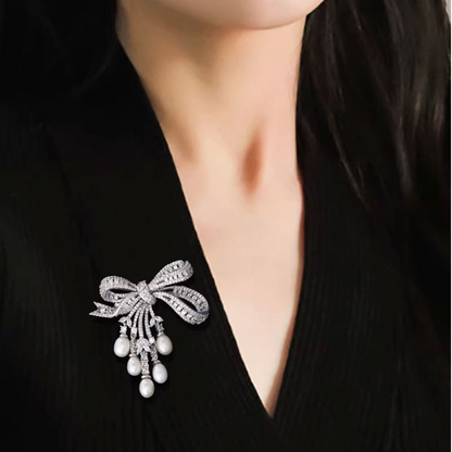 A delicate and luxurious brooch with bow-shaped tassels and a slightly set zirconia embellishment, along with freshwater pearl pins as accessories.